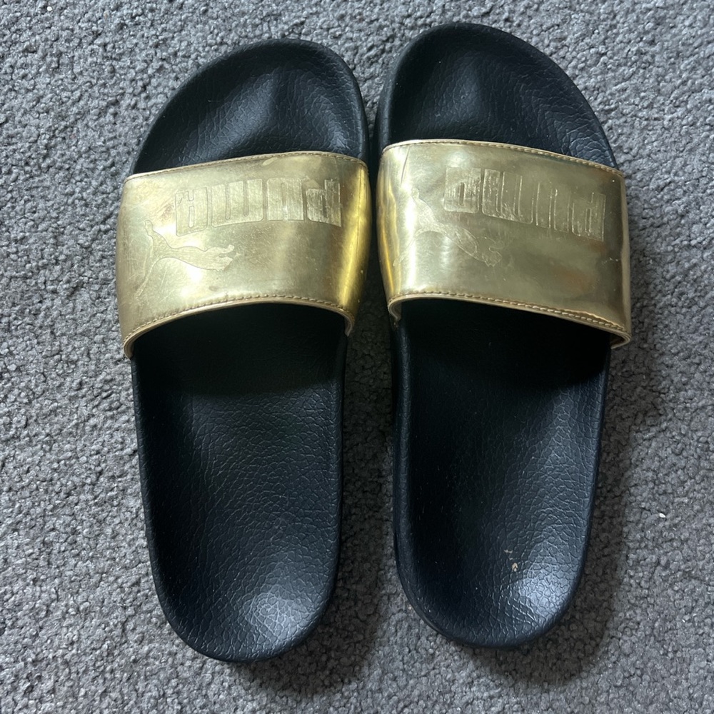 Gold and black Puma slides